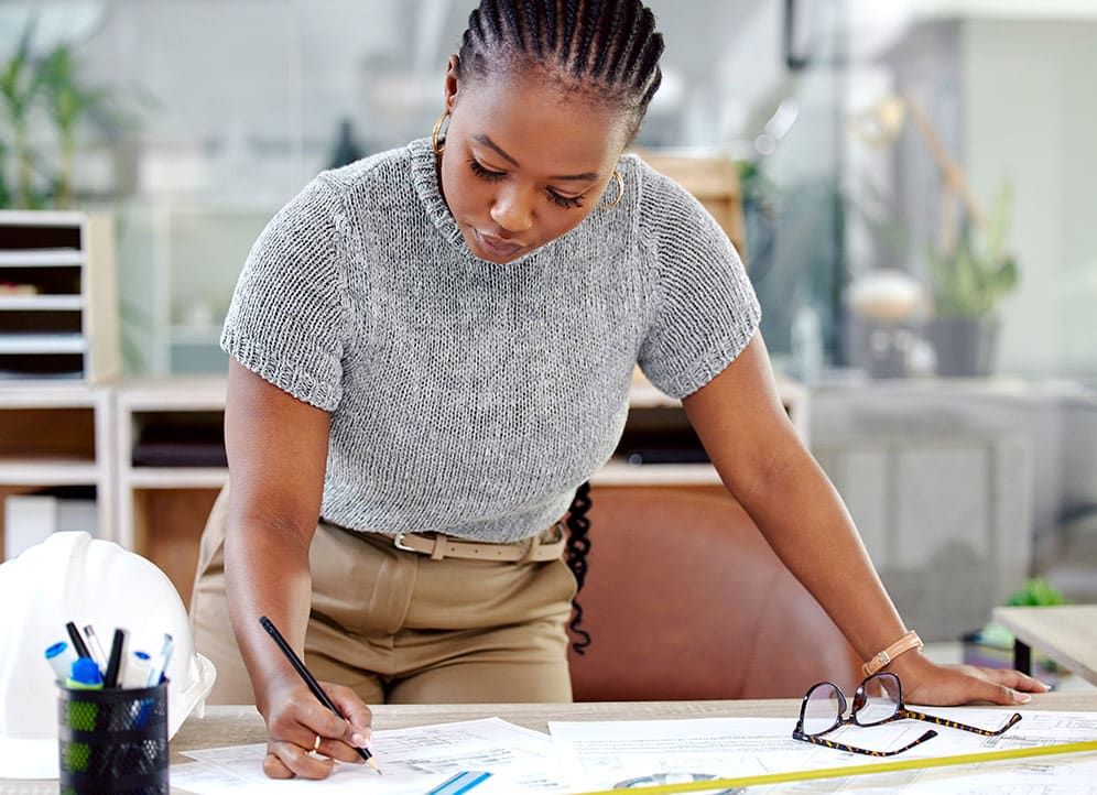 Architect working on blueprint plans at desk 2