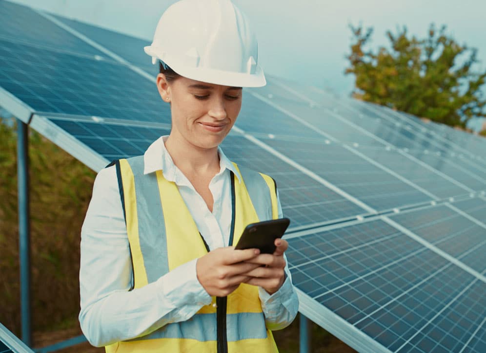 Construction worker text messaging client while standing by solar panels