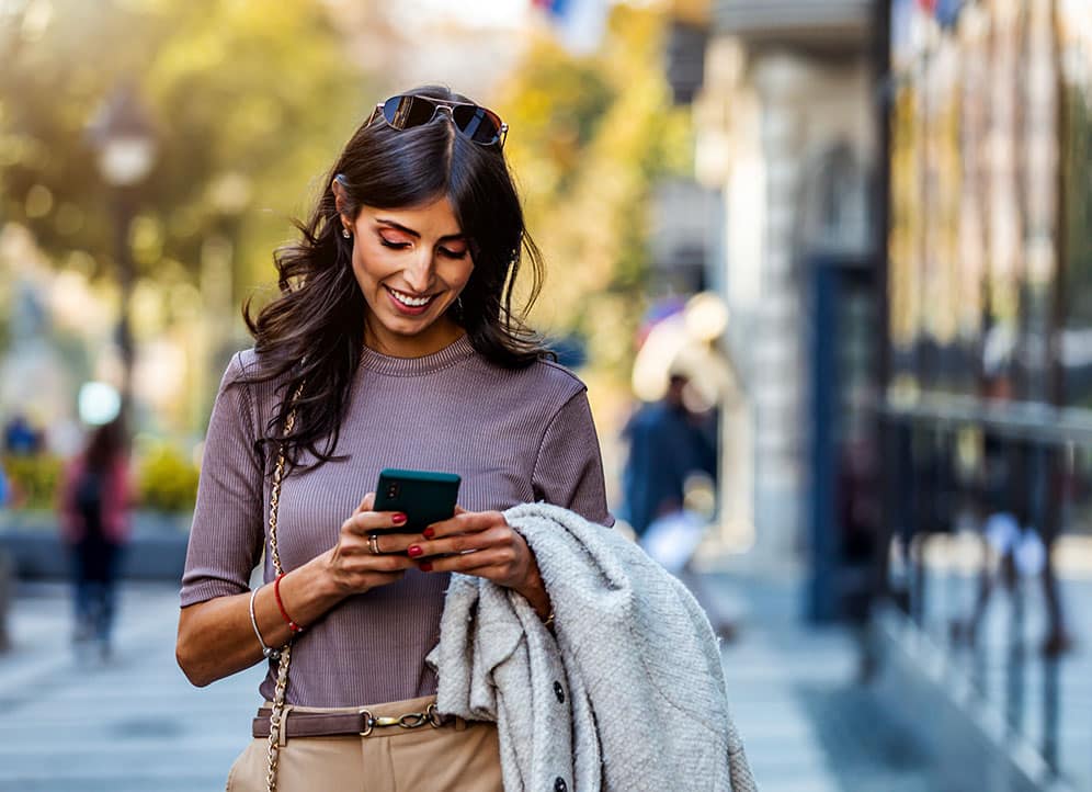 Professional woman walking down street and messaging client