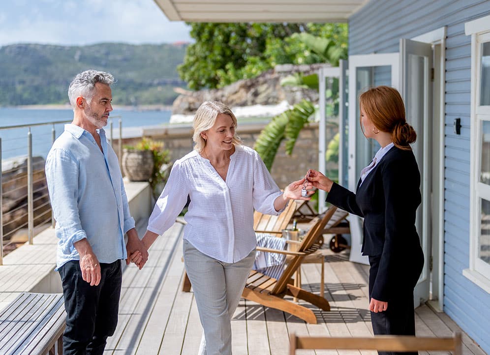 Couple getting key from realtor at house