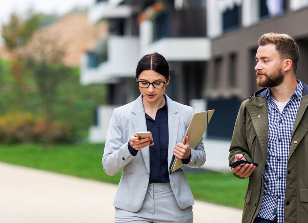 Real estate colleagues walking and sharing text messages