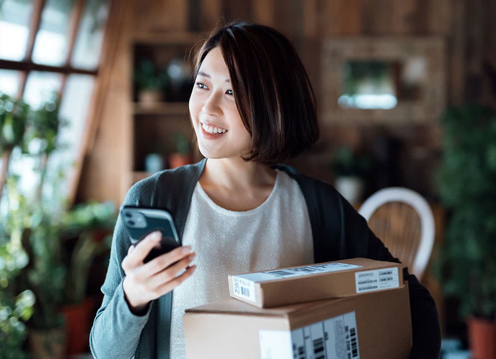 Woman text messaging customer while holding packages