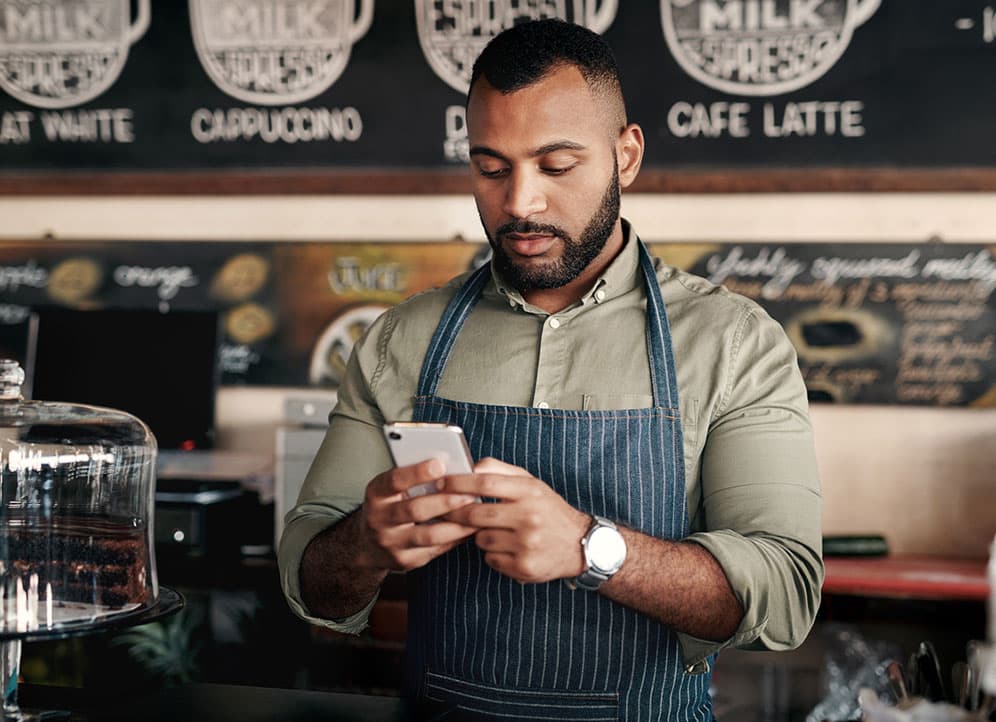 Man text messaging customers while working in coffee shop